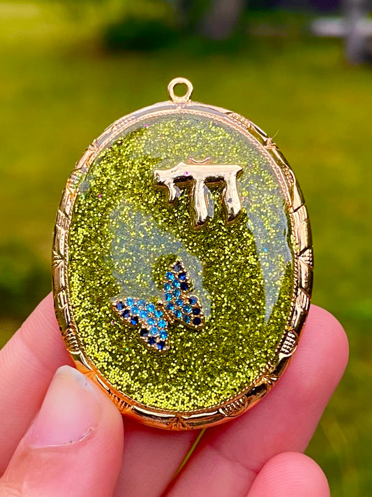 Mossia Pendant 2: gold plated Chai, Blue Butterfly with Green Glitter in Resin